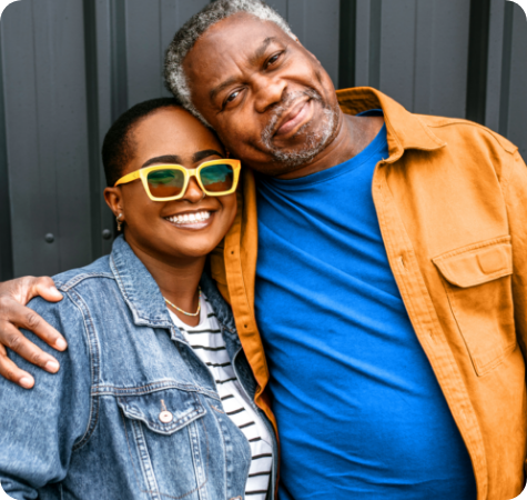 A father with his arm around his daughter, both smiling